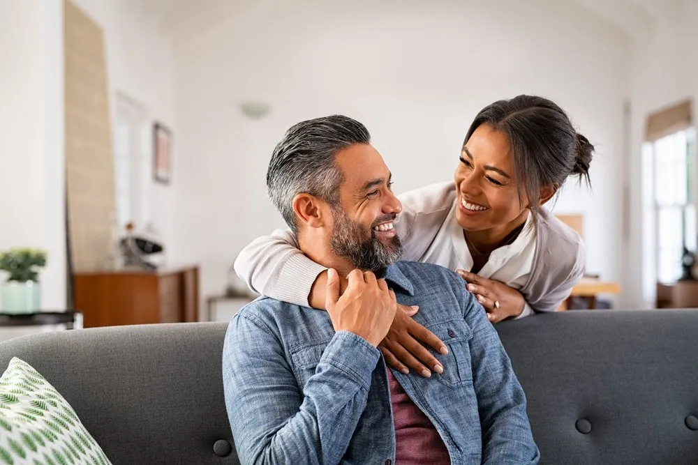 A couple sitting together on a couch, smiling