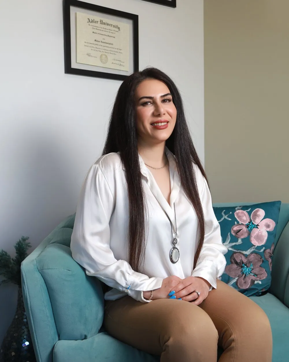 Mahsa Hamedanizadeh, Registered Clinical Counsellor, sitting on a teal sofa in the Langley office