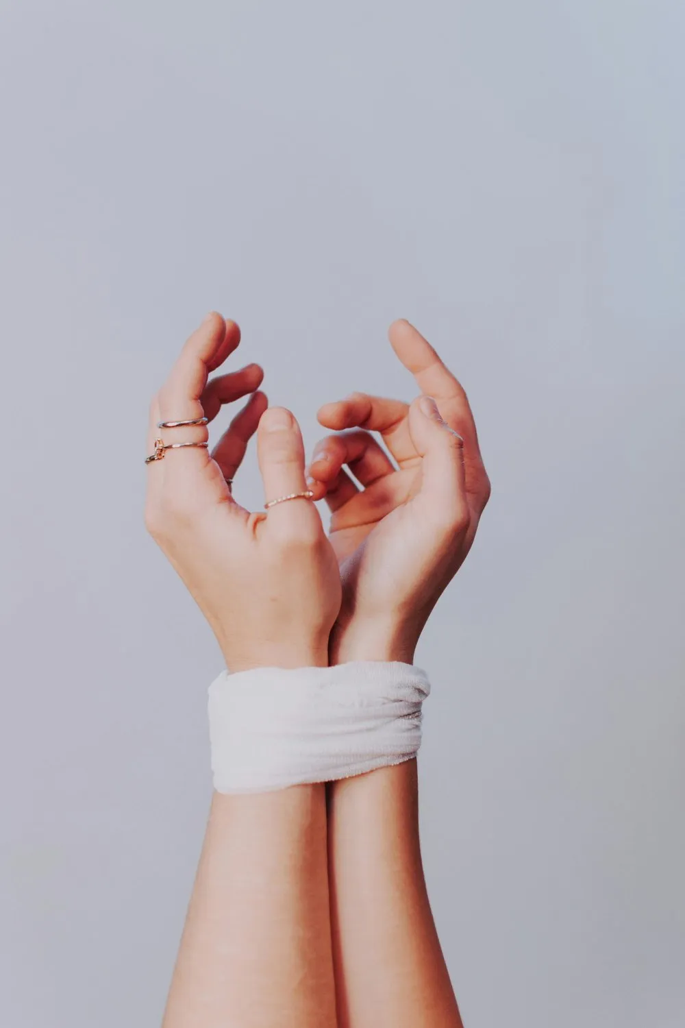 A person’s hands resting, wearing rings
